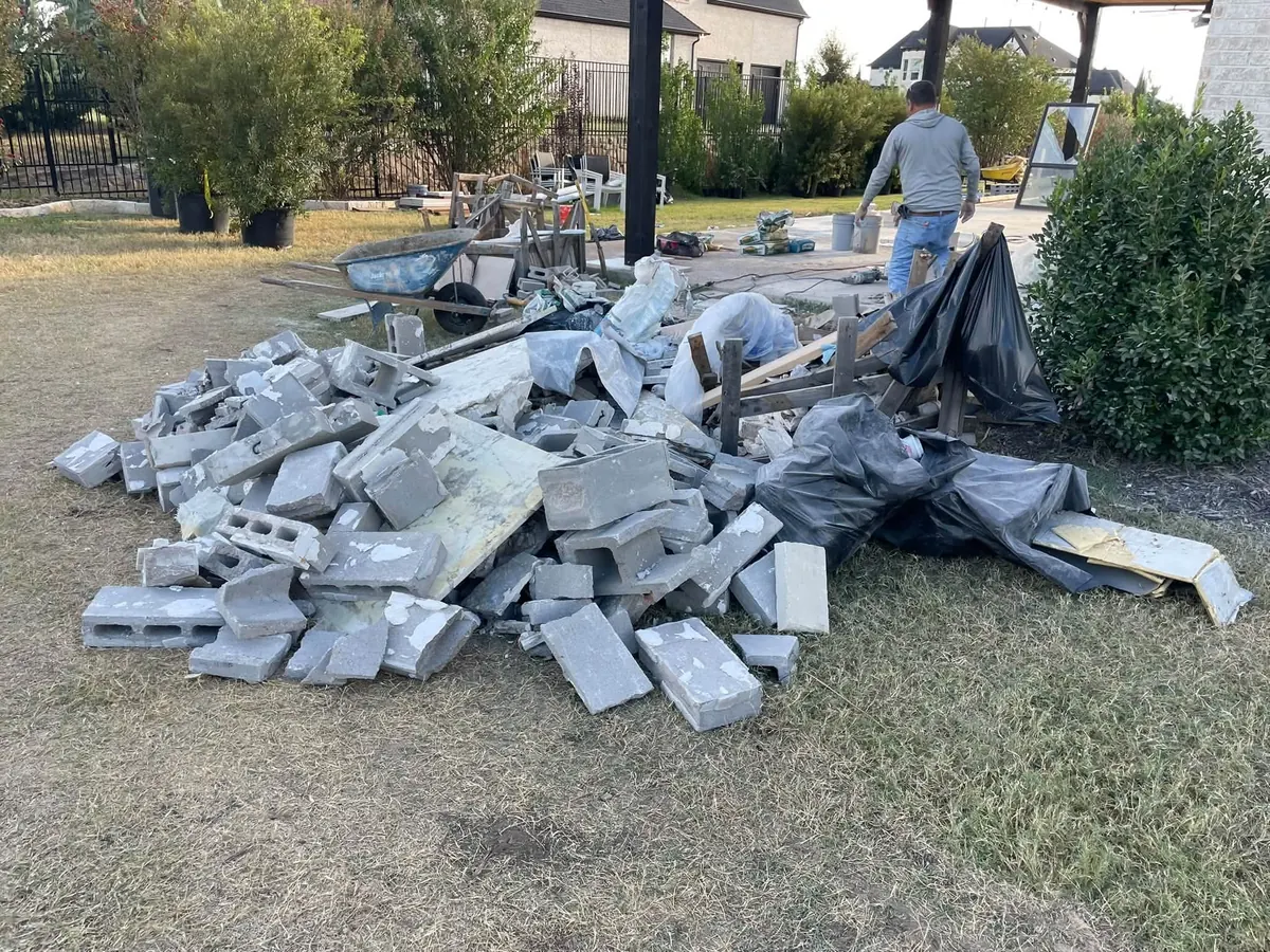 Broken concrete blocks and tarps piled on a lawn