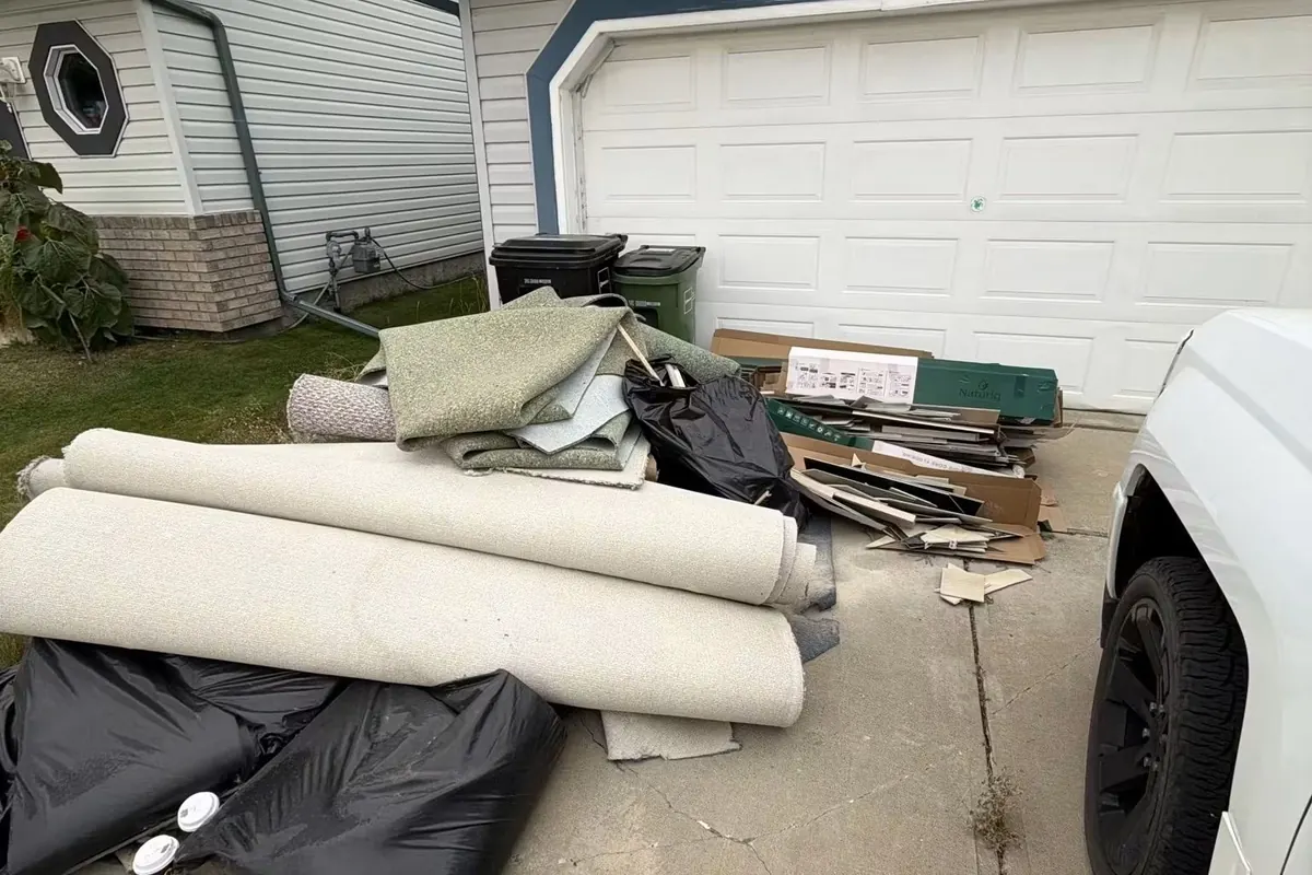 Rolled carpet and junk stacked in a driveway